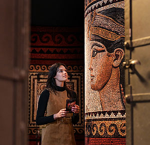 Besucherin in der Ausstellung beim Betrachten eines Mosaiks