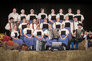 Das Akkordeon-Orchester Gutach e.V. in der Tracht des Gutacher Tals: Weiße Bluse, schwarzer Rock, blaue Schürze. Die Männer in schwarzer Hose und weißem Hemd. 